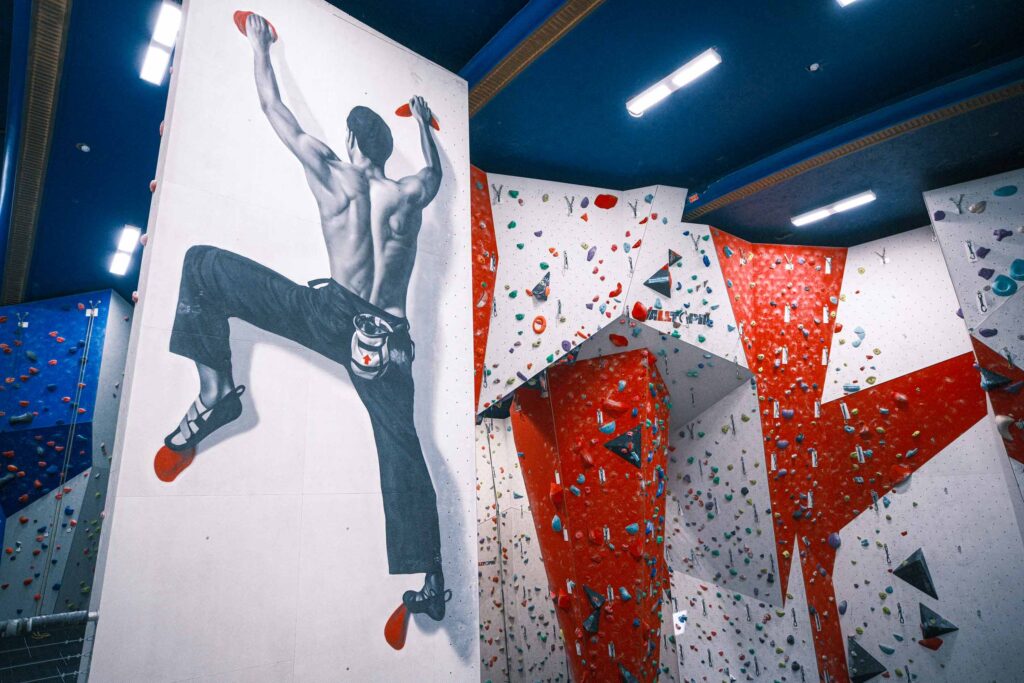Wide view of Redpoint Bristol climbing centre featuring a large climber mural alongside steep lead climbing walls with colourful holds and varied routes.