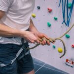 Close-up of a climber tying a secure knot into a climbing rope while wearing a harness at the indoor climbing walls of Redpoint Bristol.