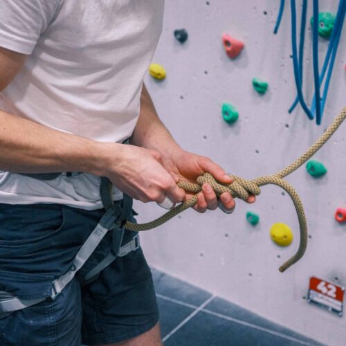 Close-up of a climber tying a secure knot into a climbing rope while wearing a harness at the indoor climbing walls of Redpoint Bristol.